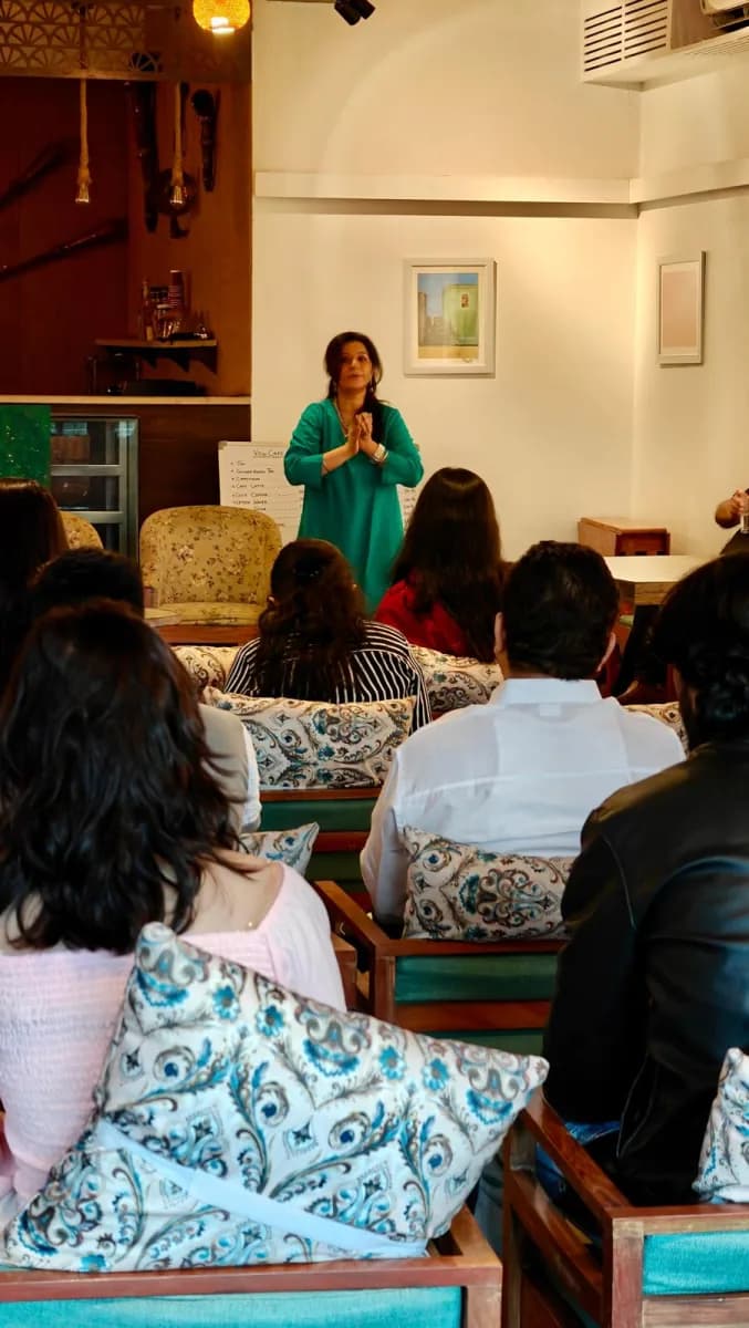 Charu Wadhwa greeting a full room with folded hands at VOW Café, Dehradun